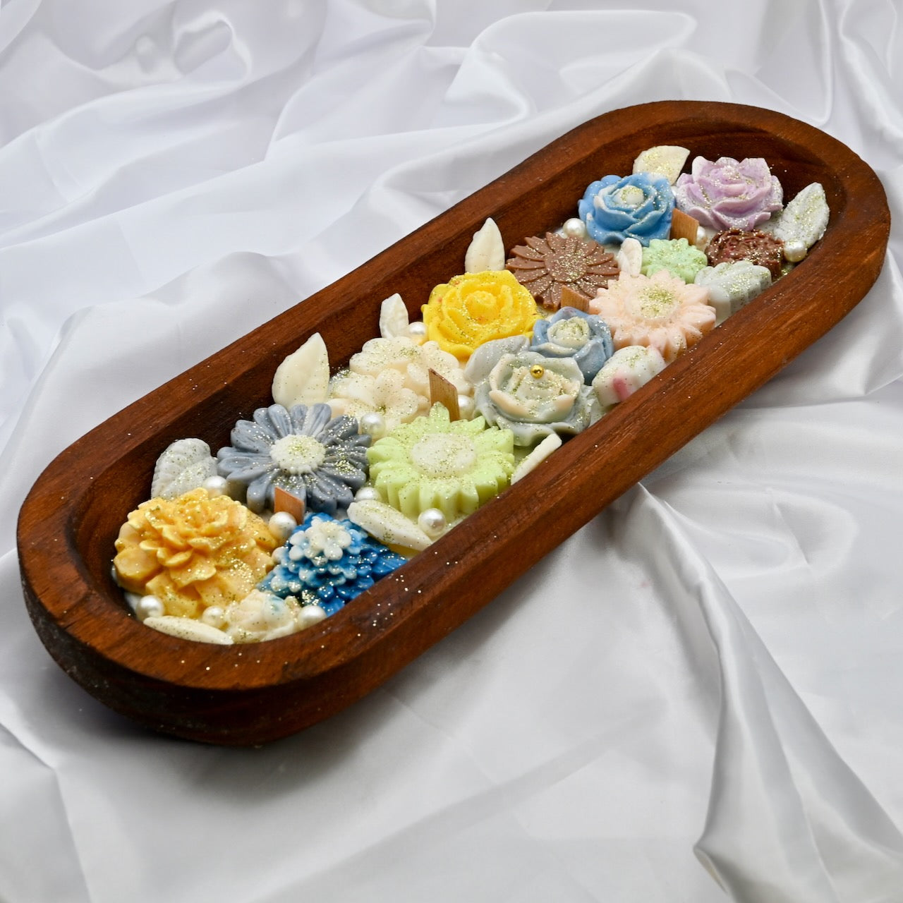 Wooden tray with multiple floral-shaped colorful yellow, blue, pink candles