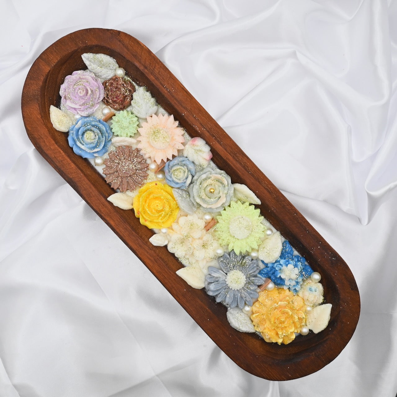 Top view of wooden tray with multiple floral-shaped colorful yellow, blue, pink candles