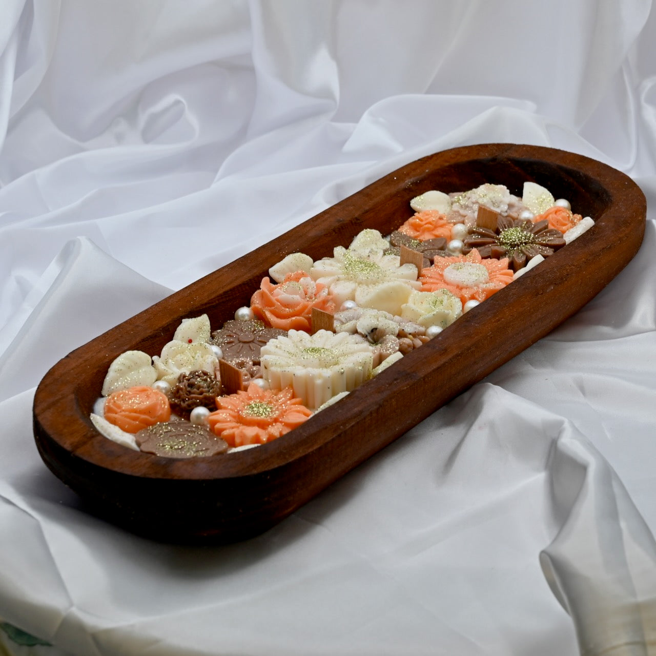 Right view of wooden tray with multiple floral-shaped colorful pink and brown candles