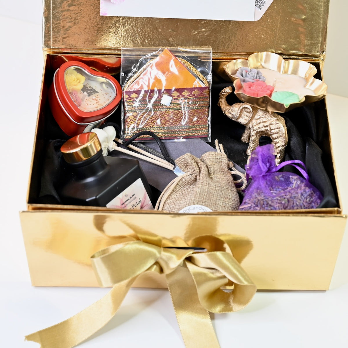 Large gold-finish gift box showing elephant urli candle, heart tin candle, lavender pouch, essential oil pouch, and room diffuser