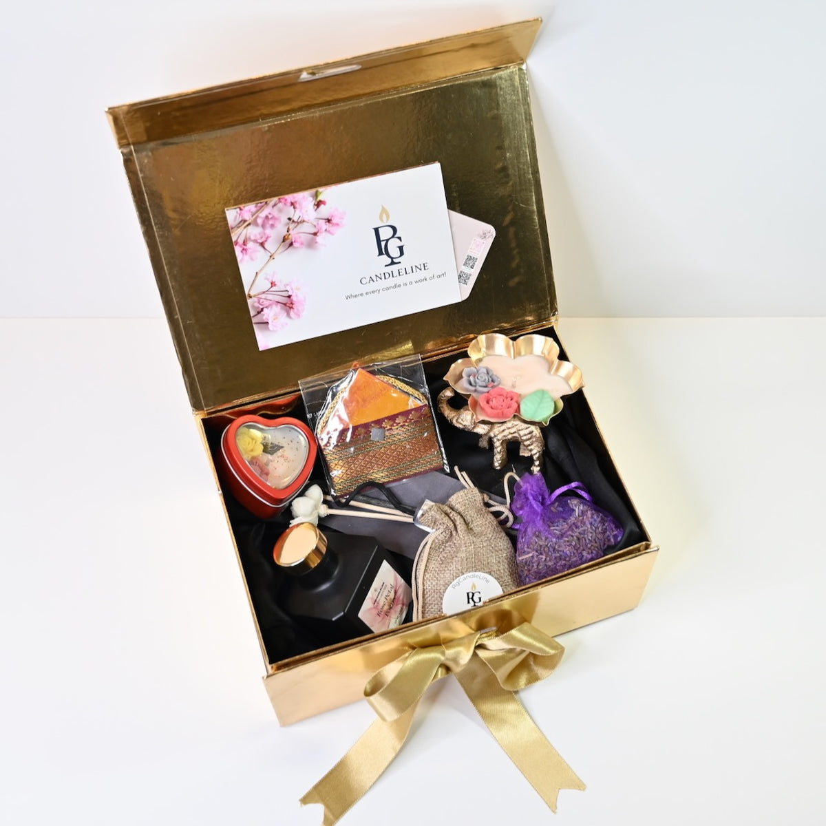 Top view of large gold-finish gift box with candle hamper contents