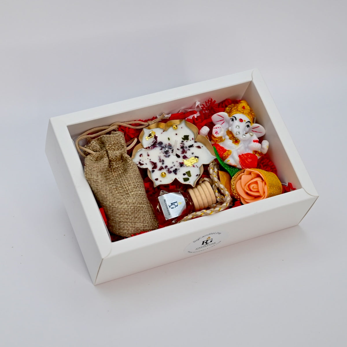 Medium white gift box showing candle, Ganapati accent, car diffuser, decorative flower, and small bag contents