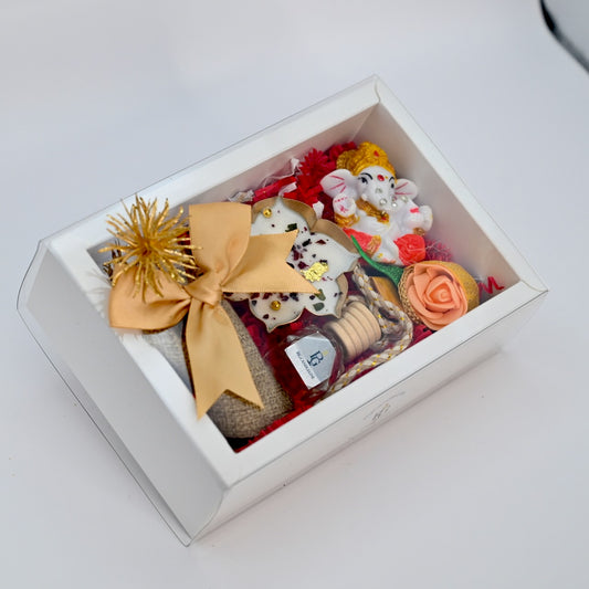 Top view of medium white gift box with candle, Ganapati accent, car diffuser, decorative flower, and small bag