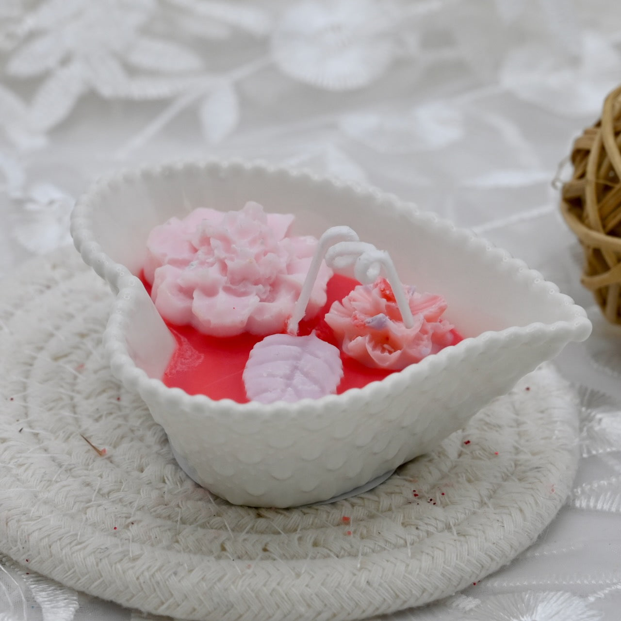 Decorative candle with white  pink flowers, and pink accents in a white ceramic heart shaped container.