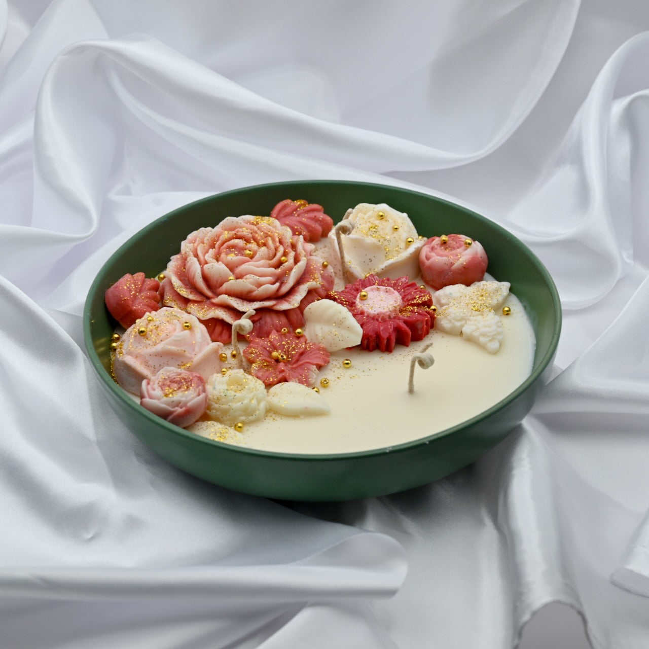 Left view of green bowl candle with pink and blush floral wax design and gold accents