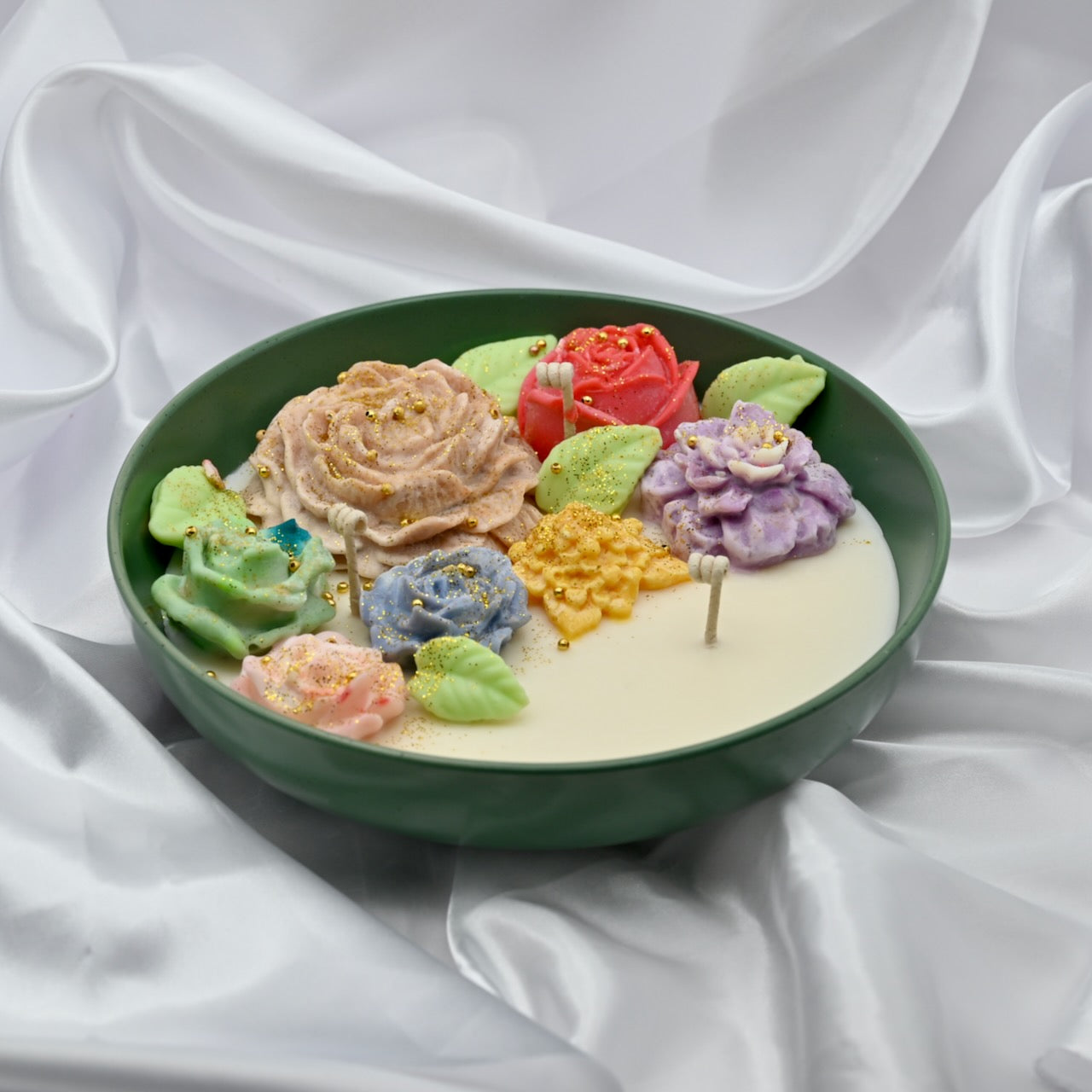 Left view of green bowl candle with multicolor floral wax design and gold accents