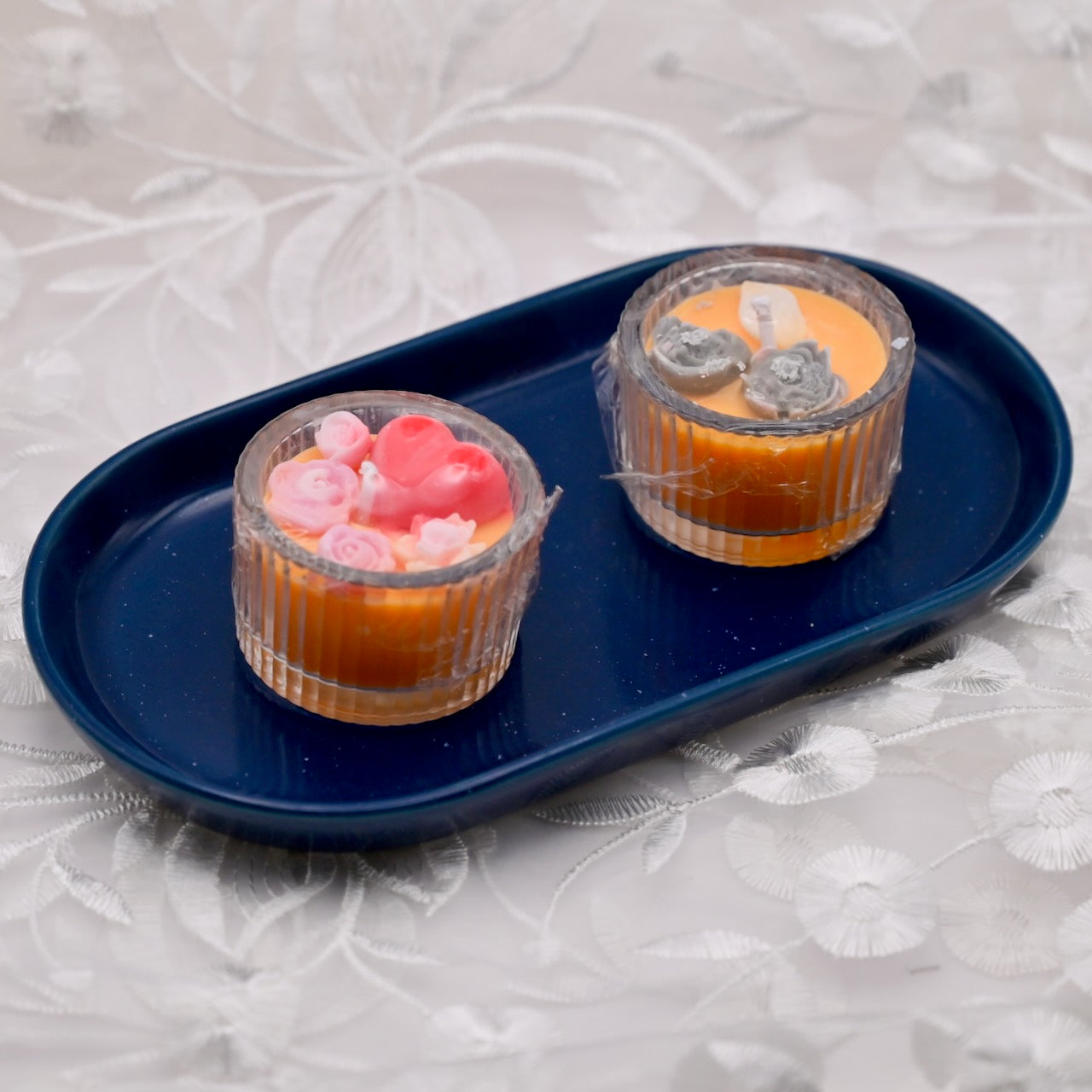 Two orange mini glass candles with decorative colorful flowers on the top