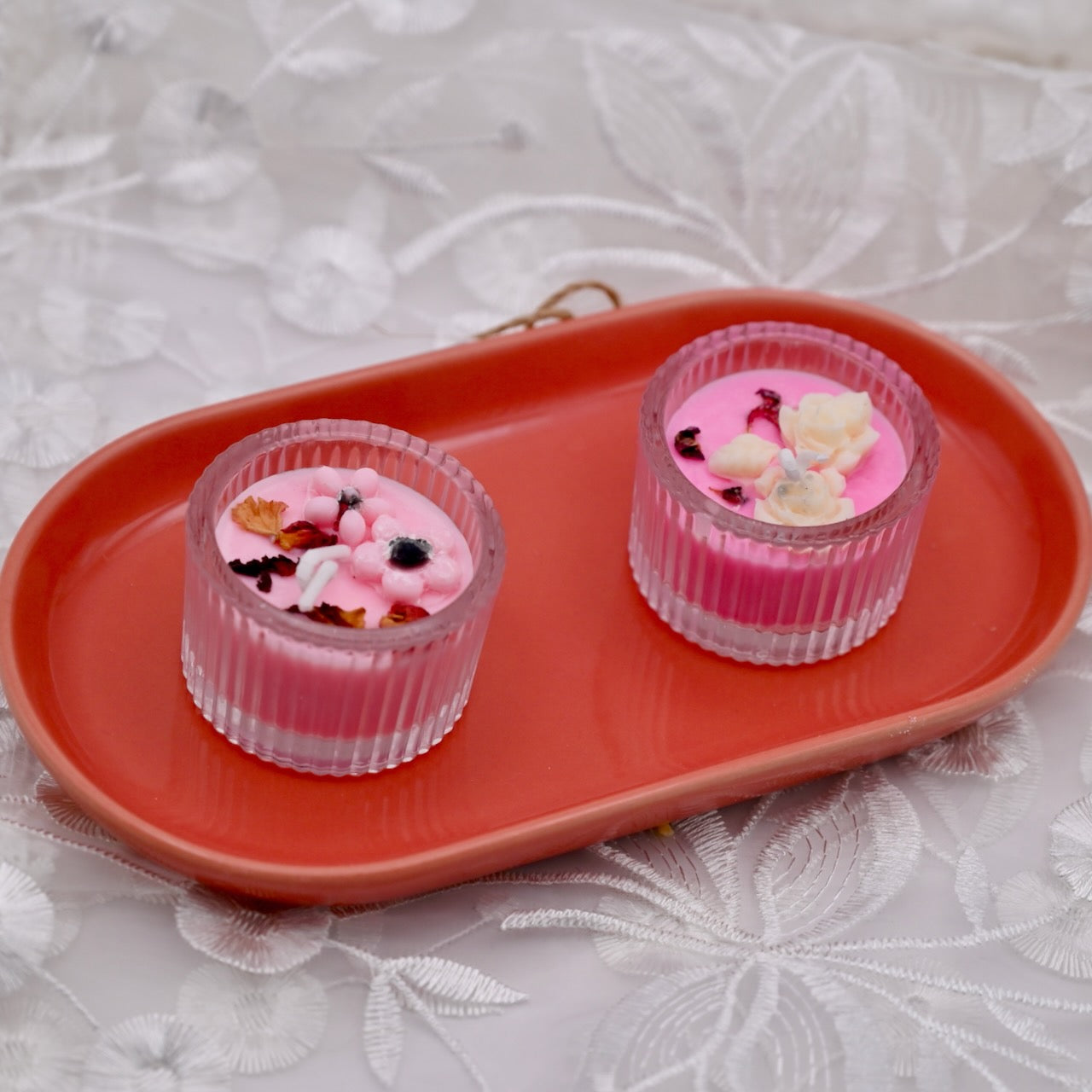 Two pink mini glass candles with decorative flowers on the top