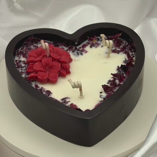 Video of heart-shaped candle with red and white design on a white fabric background