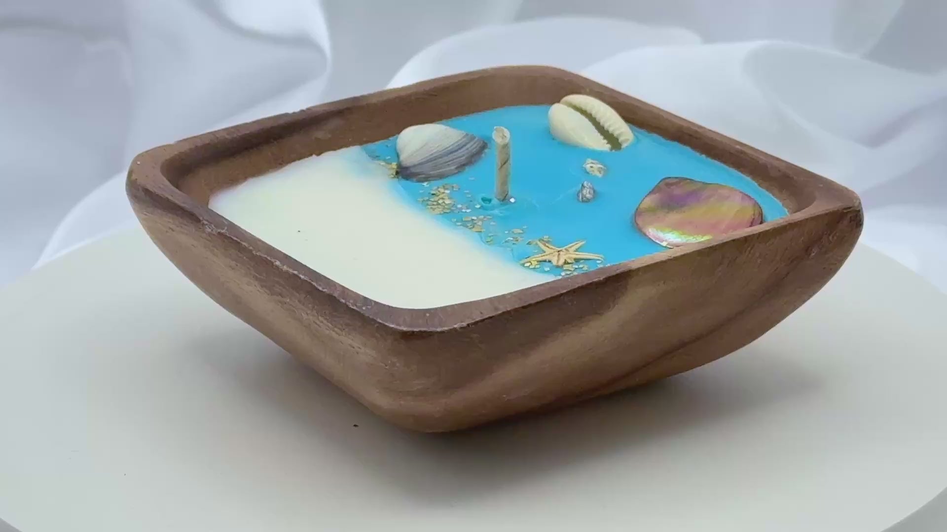 Video of  square acacia wood bowl candle with seashell and starfish wax details
