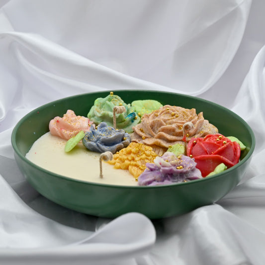 Right close up of green bowl candle with multicolor floral wax design and gold accents