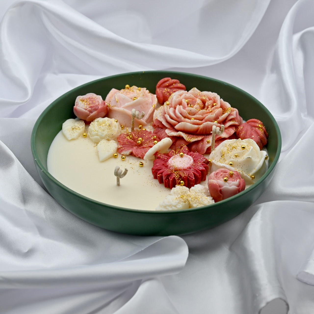 Right close up view of green bowl candle with pink and blush floral wax design and gold accents
