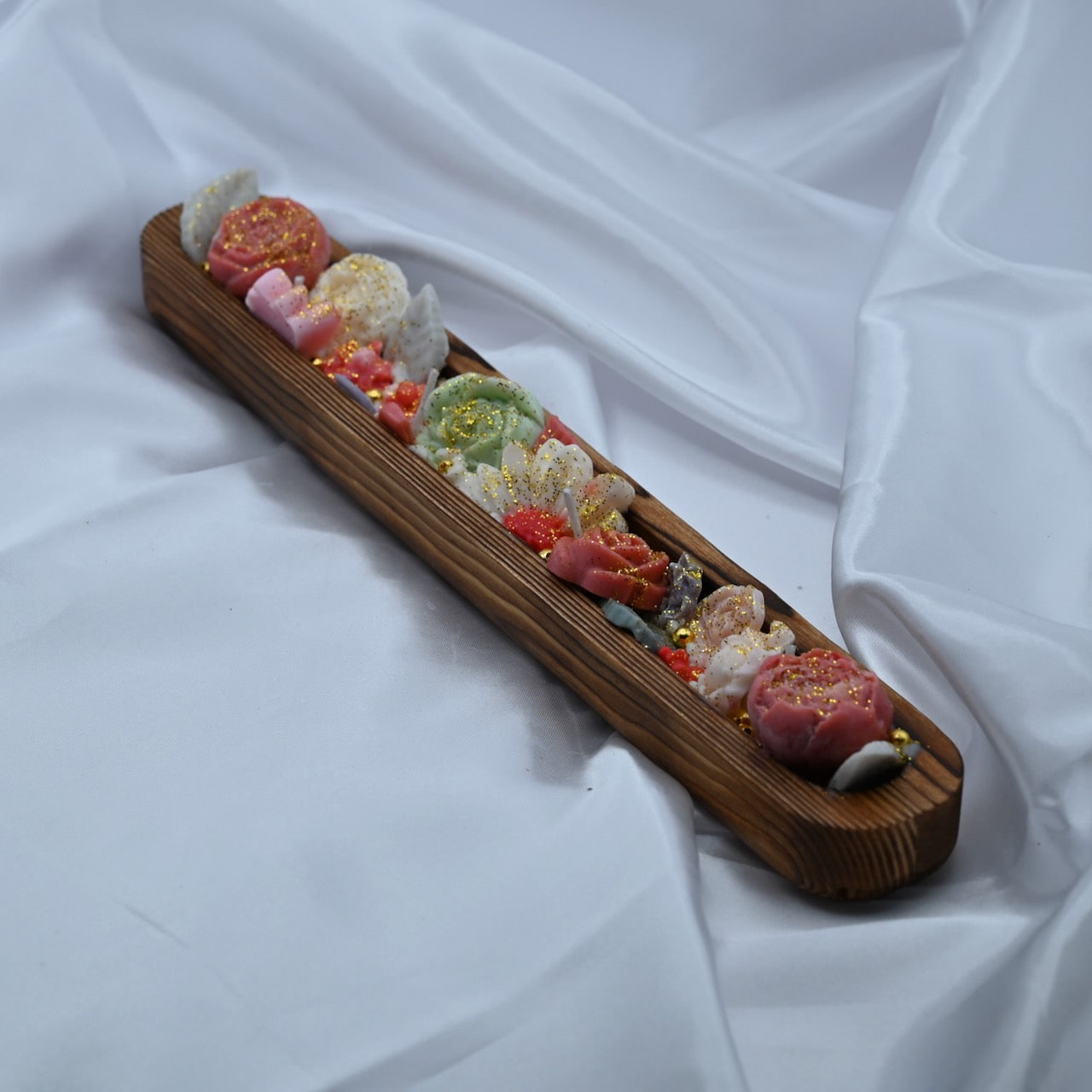 Left view of wooden dough bowl candle with pink and green floral wax design and gold shimmer accents