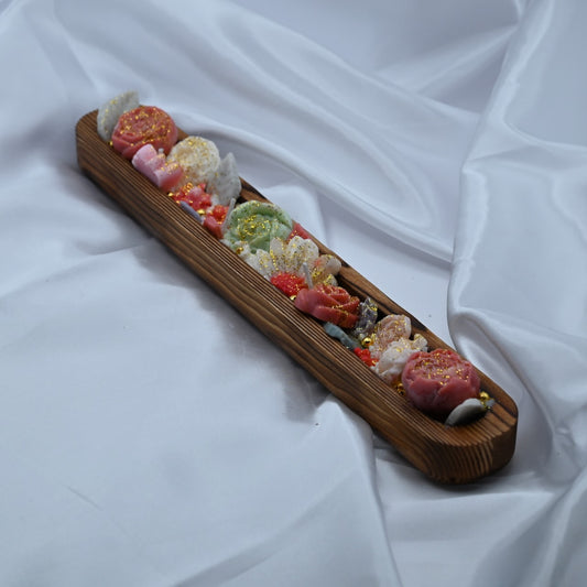 Left view of wooden dough bowl candle with pink and green floral wax design and gold shimmer accents