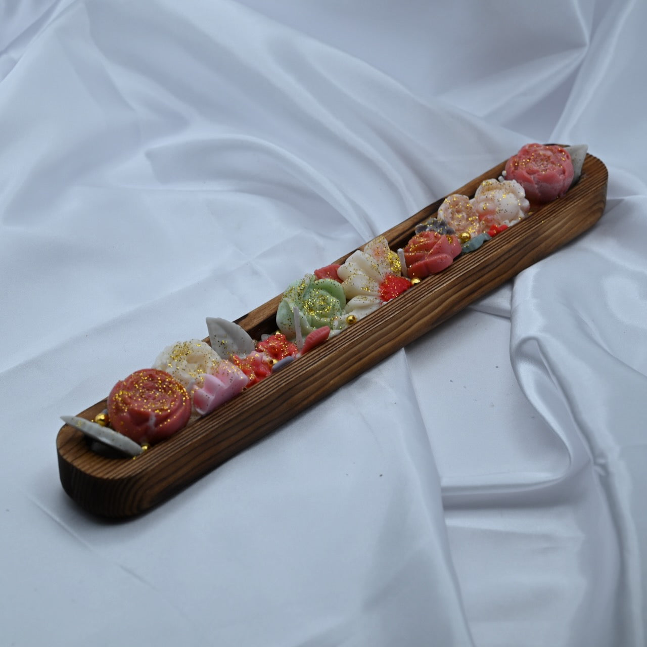 Right view of wooden dough bowl candle with pink and green floral wax design and gold shimmer accents.