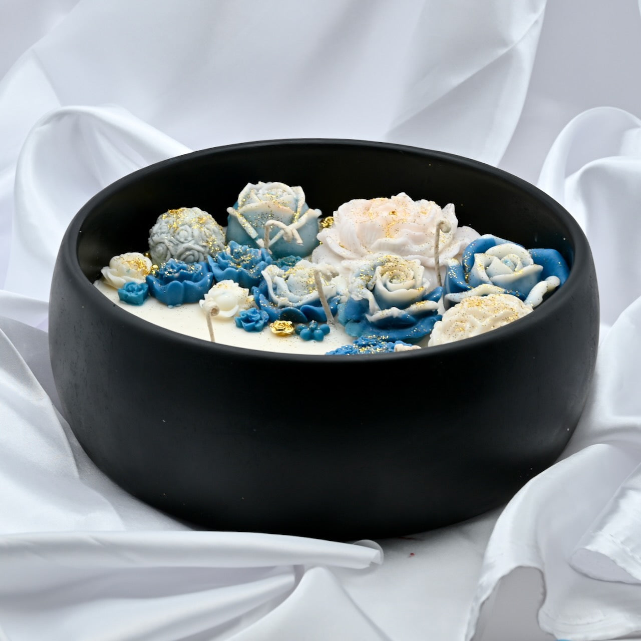 Top right view of black acacia wood bowl candle with blue and white floral wax design and gold accents