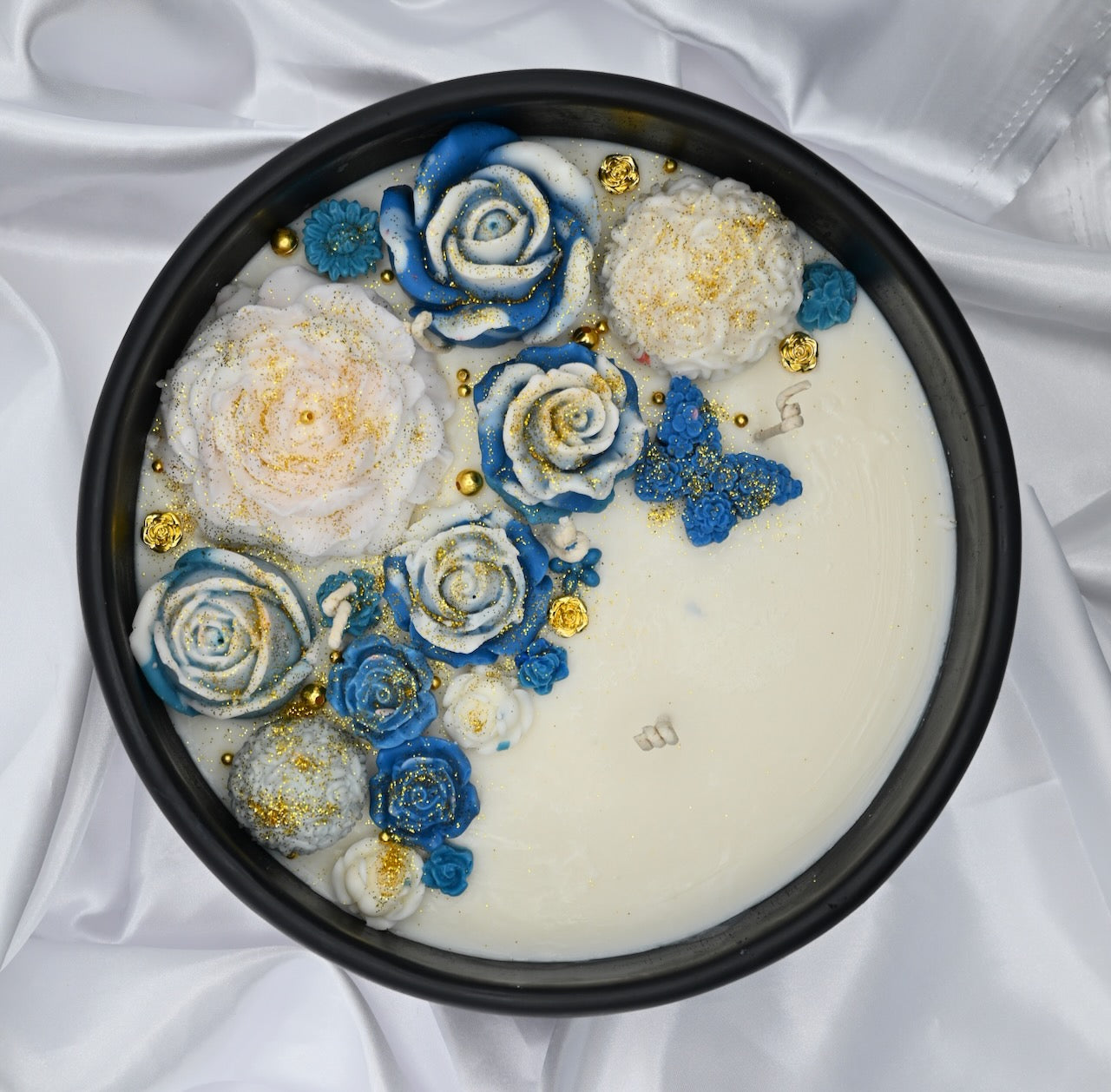 Top right view of black acacia wood bowl candle with blue and white floral wax design and gold accents