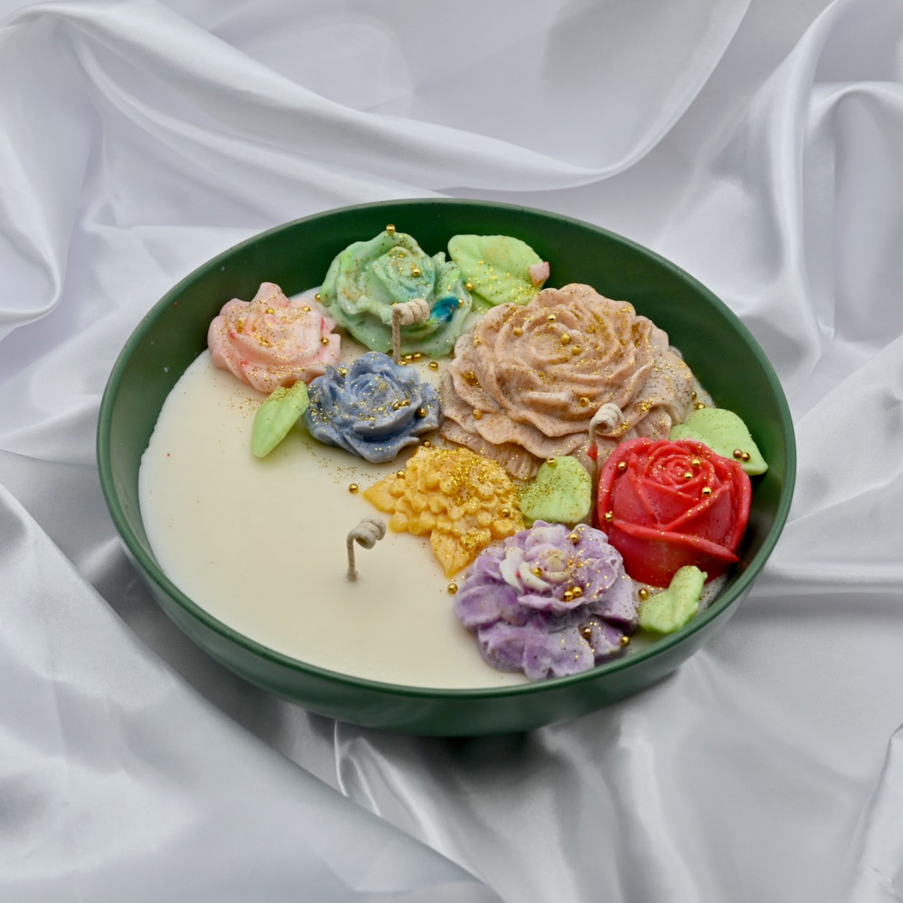 Top right view of green bowl candle with multicolor floral wax design and gold accents