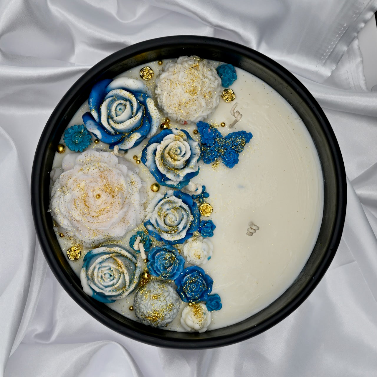 Top view of black acacia wood bowl candle with blue and white floral wax design and gold accents