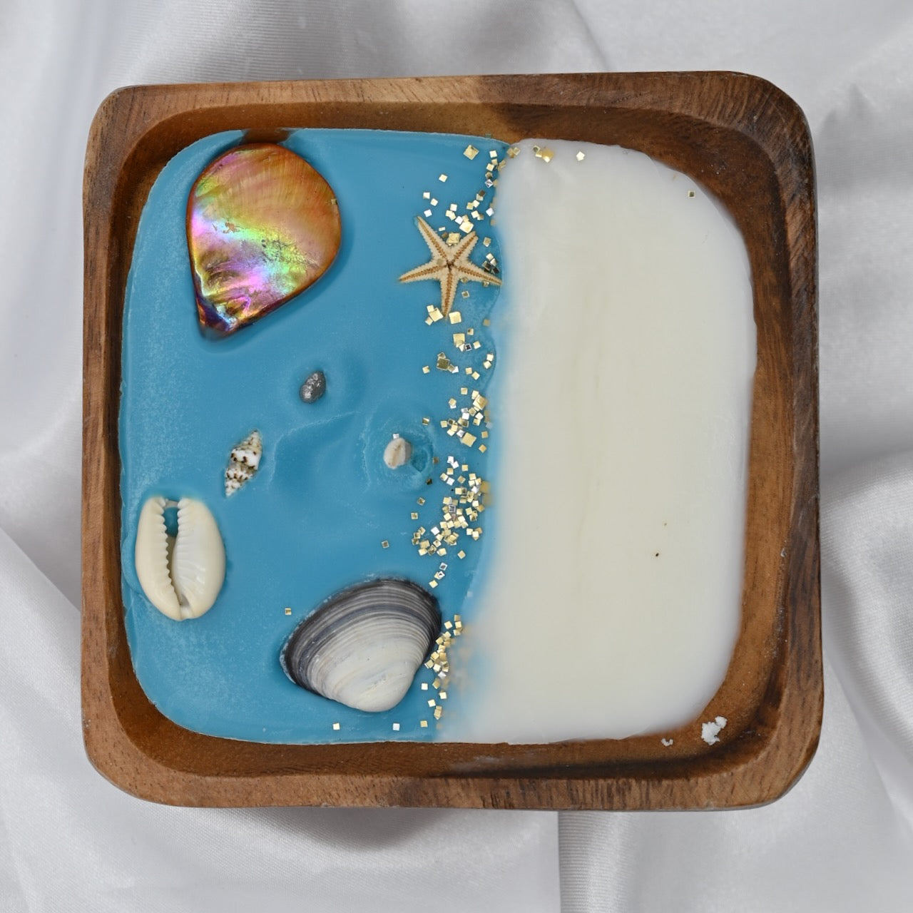 Top view of square acacia wood bowl candle with seashell and starfish wax details