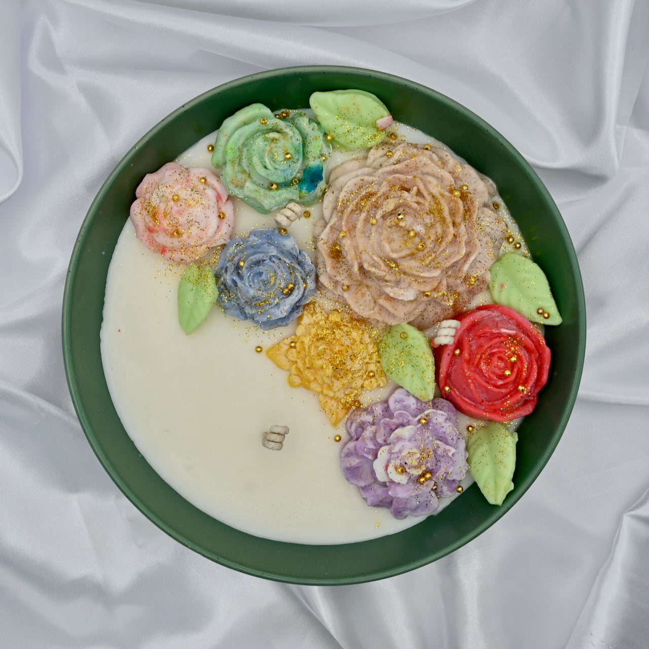 Top view of green bowl candle with multicolor floral wax design and gold accents